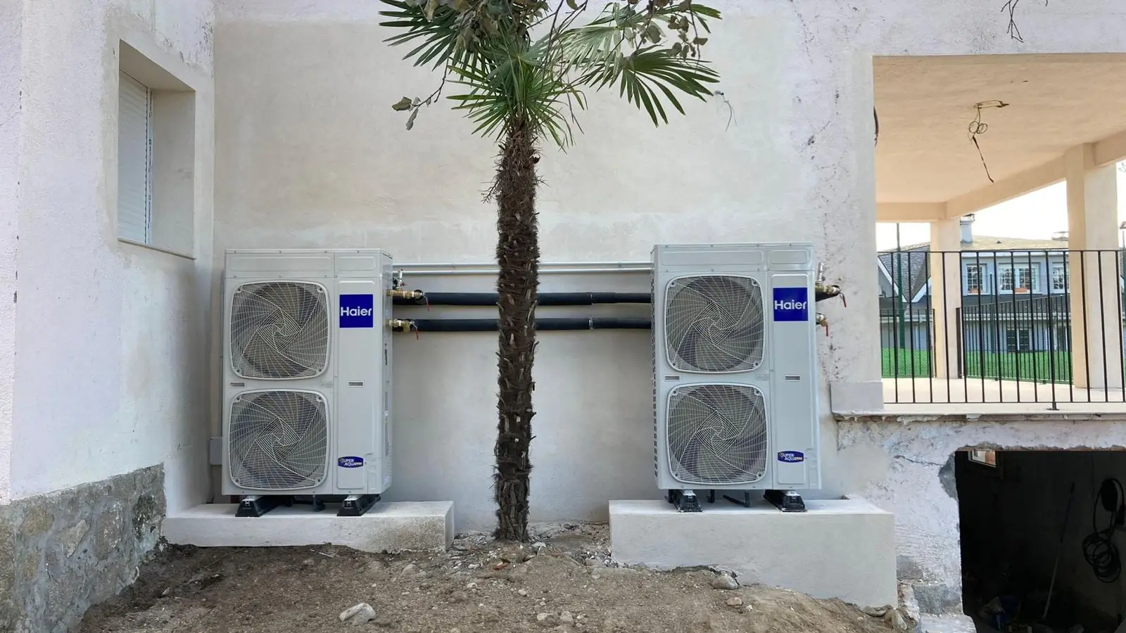 Dos máquinas exteriores de aerotermia instaladas en cascada sobre sus bases en el jardín de una vivienda unifamiliar