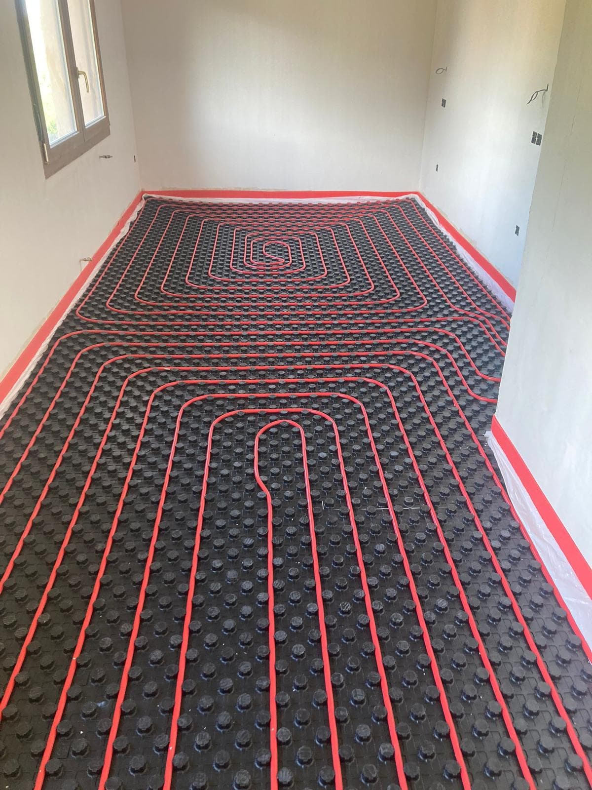 Circuitos de suelo radiante en otra habitación de la vivienda, con las tuberías ancladas al panel